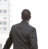 A businessman in silhouette standing at a large window in a convention center lobby.