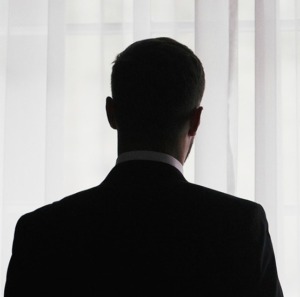 Stylish groom silhouette in suit posing at window light